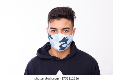 Young 20 year old boy with personalized protective mask on his face, to protect himself from the coronavirus on white background, looking at camera
