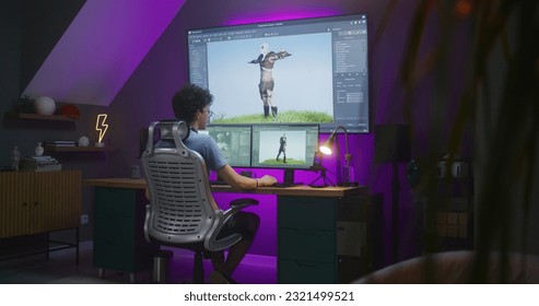 Young 3D designer creates animation for video game character, works remotely from home late night on computer and big digital screen with professional software interface for 3D modeling and design.