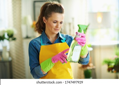 young 40 years old woman in orange apron and pink rubber gloves with spray bottle of eco friendly cleaning supplies reading instruction in the modern house in sunny day. - Powered by Shutterstock