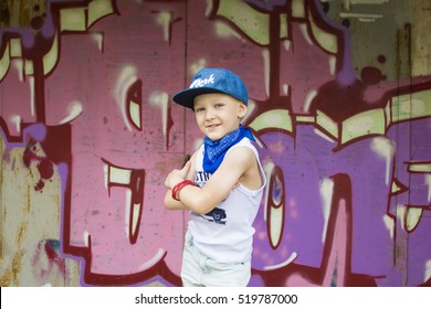 young 5-years boy posing in front of a colorful graffiti wall. Teenager boy dancing hip hop over textured background