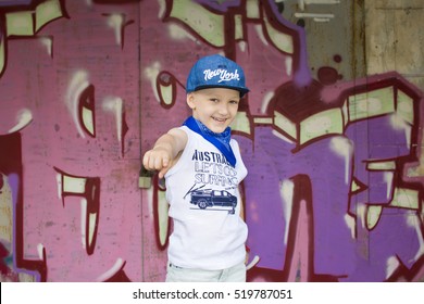 young 5-years boy posing in front of a colorful graffiti wall. Teenager boy dancing hip hop over textured background
