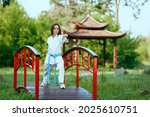 Young active girl wearing in white kimono with blue belt performing martial arts  kick skills. sporty karate woman improving  fight technique on Chinese bridge. concept of sport.