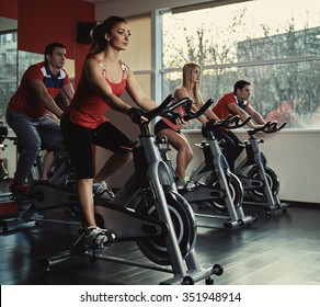 Young active people exercising in spinning class. Group of fit people doing sport in the gym.
