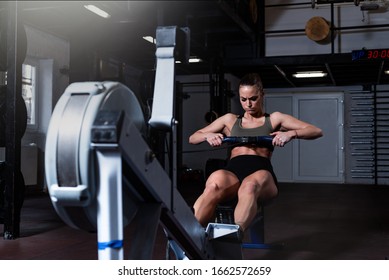 Young Active Strong Fit Sweaty Powerful Attractive Muscular Woman With Big Muscles Doing Hard Core Row Heavy Crossfit Training Workout On Indoor Rower At The Gym Real People Exercise