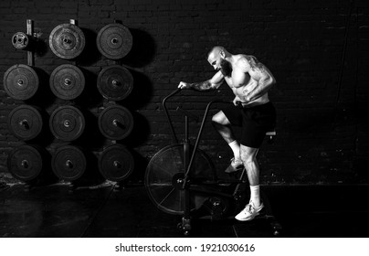 Young active strong fit sweaty muscular man with big muscles doing cardio workout in the indoor air bicycle in the gym as hardcore cross training real people exercise - Powered by Shutterstock