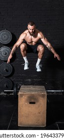 Young active strong fit sweaty muscular man with big muscles doing box jump workout in the gym as hardcore cross training real people exercise