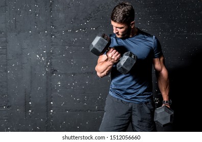 Young Active Strong Muscular Sweaty Man Biceps Muscle Workout Training With Heavy Dumbbell Weight In The Gym Dark Image With Shadows Real People Exercising