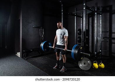 Young active strong sweaty muscular fit man with big muscles doing hardcore deadlift or weightlift workout cross training with heavy barbell weights in the gym. Male sportperson strength lifting 