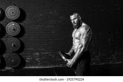 Young active sweaty strong muscular fit man with big muscles holding heavy barbell weight plate in his hands preparing for hardcore shoulder workout cross training in the gym real people exercising