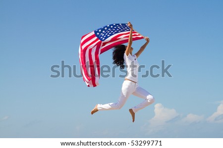 young active woman holding american flag and jumping on beach