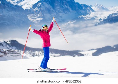 Young Active Woman Skiing In Mountains. Female Skier Kid With Safety Helmet, Goggles And Poles Enjoying Sunny Winter Day In Swiss Alps. Ski Race For Adults. Winter And Snow Sport In Alpine Resort.