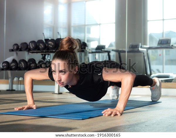 Young active woman workout push ups bodybuilding\
at the gym. Beautiful muscular slim body female practice plank\
exercises at fitness sport. Endurance training lifestyle and\
healthy motivation\
concept.