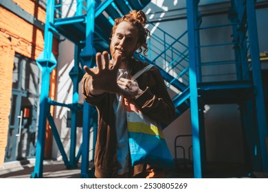 Young activist with dyed red hair and reusable shopping bag gesturing stop sign with his hand, fighting for climate change - Powered by Shutterstock