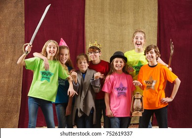 Young Actors Holding Costume Pieces Smile And Pose For The Camera