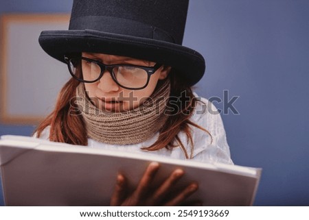 Young actress carefully reading a script while wearing a top hat, glasses, and a scarf, preparing for a theatrical performance