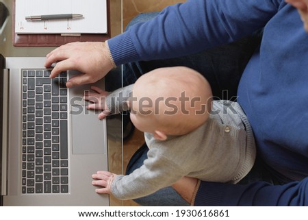 Young administrative man teleworking and taking care of his 6-month-old baby. family conciliation
