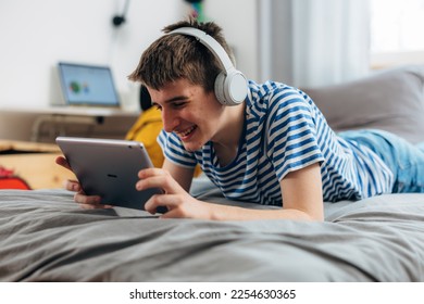 Young adolescent boy uses tablet at home - Shutterstock ID 2254630365