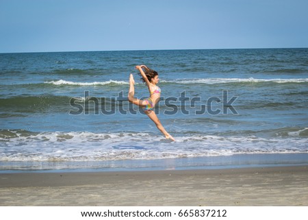 Young adolescent girl dancer on the beach leaping in the air