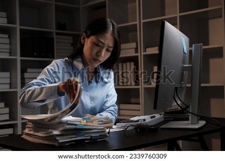 Young adorable Asian businesswoman working with work document during the night, working overtime at night.