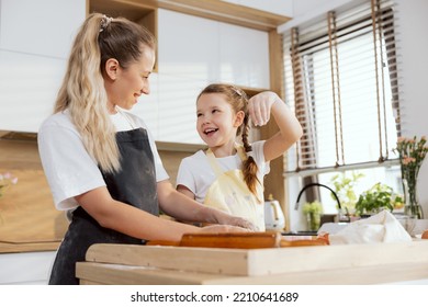 Young Adorable Mother Teaching Kid Kneading Dough Preparing Domestic Cookies Biscuits Apple Pie Surprise For Family. Girls Enjoying Process Laughing Having Fun Together At Weekend Baking Cooking.