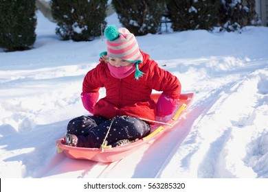 young adorable  school age girl riding on sled in the snow during winter