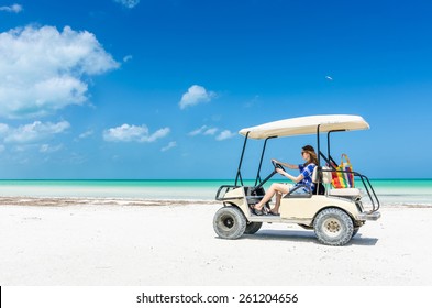 Young adorable woman driving on a golf cart along tropical white sandy beach during her Caribbean vacation on Holbox island, Mexico