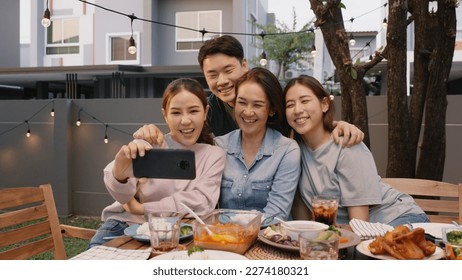 Young adult asia people hug love care for mom taking photo selfie video on mobile phone camera at home picnic dining fun night party dine table. Relax older mum smile enjoy warm time happy hour meal. - Powered by Shutterstock