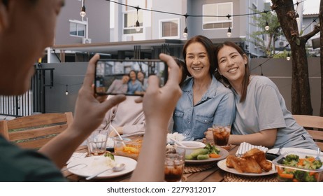 Young adult asia people hug cuddle kiss love care for mom taking photo selfie video on mobile phone camera at home picnic dining fun night party dine table. Relax older mum smile enjoy warm time meal. - Powered by Shutterstock