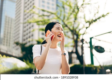 Young adult asian business single woman using mobile phone talking with friend. Happy face and laugh. City lifestyle working people. Backgroud at outdside on day.