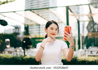 Young adult asian business single woman using mobile phone video call with friend. Happy smile face. City lifestyle working people. Backgroud at outdside on day.