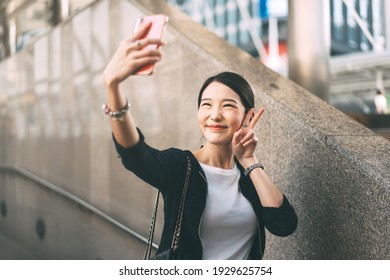 Young adult asian business single woman using mobile phone selfie and video call. Happy smile face. City lifestyle working people. Backgroud at outdside on day.