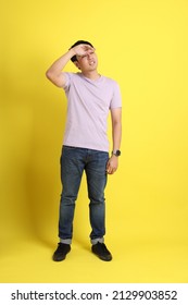 The young adult Asian man standing on the yellow background.