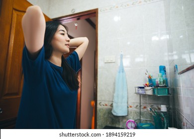 Young Adult Asian Woman Practice Self And Checking By Mirror In Bathroom At Home. Mental Health Maintain Lifestyle After Wake Up Concept.