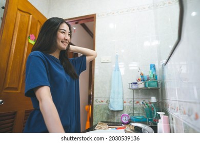 Young Adult Asian Woman Practice Self And Checking By Mirror In Bathroom At Home. Mental Health Maintain Lifestyle After Wake Up Concept. Eye Looking Camera.