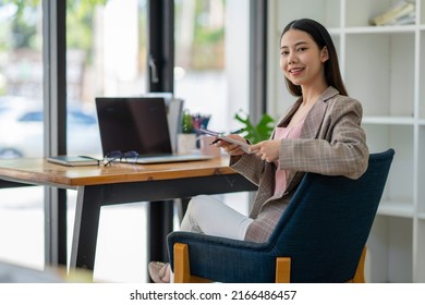 Young Adult Asian Women Work At Home Or Modern Office, Using A Notebook Laptop Computer. Work From Home Life, Information Technology, Domestic Lifestyle, Or Self-isolation Working Concept