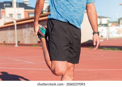 Young adult athlete man doing warm-up exercises and stretching the muscles of his legs, quadriceps and calves to avoid serious injury.