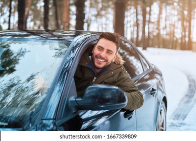 Young Adult Attractive Caucasian Man Sits At The Wheel Of His Car Sunny Winter Day. Wintertime Road Trip. Happy Smiling Hipster Guy Sitting In Car And Looking Window. Portrait Positive Driver 