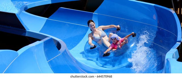 Young Adult Australian Mother (female Age 30) And Child (girl Age 04) Sliding On A Water Slide In A Water Park. Summer Holiday Family Fun Vacation Concept. Real People. Copy Space