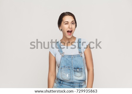 The young adult beautiful arab woman, toothy smile and wink at camera. Isolated studio shot on gray background