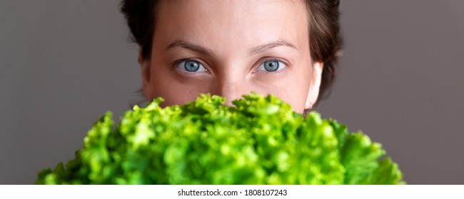 Young Adult Beautiful Caucasian Happy Smiling Woman Portrait Holding Green Fresh Lettuce Salad Front Face. Healthy Food Nutrition Concept. Green Oraganic Eco Bio Natural Vegan Meal. Wide Banner Cro