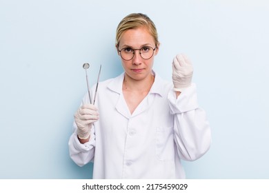 Young Adult Blonde Woman Making Capice Or Money Gesture, Telling You To Pay. Dentist Concept