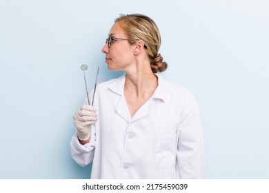 young adult blonde woman on profile view thinking, imagining or daydreaming. dentist concept