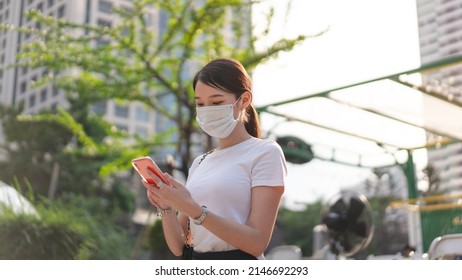 Young Adult Business Asian Woman Using Mobile Phone For Shopping Online Via Digital Wallet. Lifestyle With Technology. Single Businesswoman Wear Face Mask.