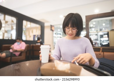 Young Adult Business Asian Woman Sipping Coffee And Using Tablet For Online Internet At Indoor Public Cafe On Day. Single People Lifestyle In City Concept.