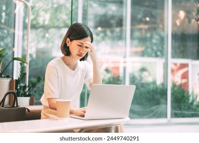 Young adult business asian woman fatique and stress at cafe. Businesswoman using laptop computer tired from working overtime. - Powered by Shutterstock