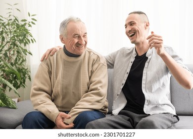 Young adult caucasian son listening and supporting his old elderly senior father at home indoors. Care and love concept. - Powered by Shutterstock