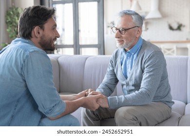 Young adult caucasian son listening and supporting his old elderly senior father at home indoors. Happy father`s day! Care and love concept. I love you, dad! - Powered by Shutterstock