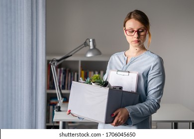 Young Adult Caucasian Woman Female Girl Standing By The Window At The Office Losing Her Job Holding Personal Items Things In Box Being Fired From Work Dismissed Due To Crisis Recession Quitting