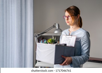 Young Adult Caucasian Woman Female Girl Standing By The Window At The Office Losing Her Job Holding Personal Items Things In Box Being Fired From Work Dismissed Due To Crisis Recession Quitting