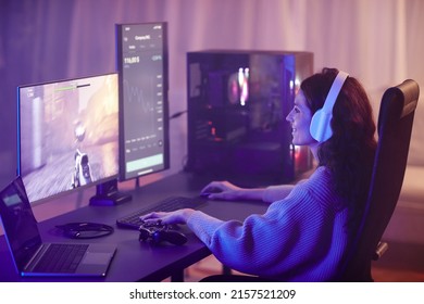 Young Adult Caucasian Woman Spending Free Time Playing Shooter Video Game On Desktop Computer In Living Room At Night